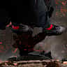 A person wearing Nike sneakers steps into a dark puddle that reflects their silhouette.