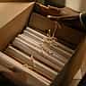 A professional in a grey suit carefully placing tied document scrolls into a cardboard archive box.