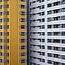 A modern apartment building facade split visually between bright yellow and clean white sections.