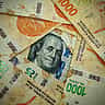 A US hundred-dollar bill surrounded by an arrangement of Argentine thousand-peso banknotes.