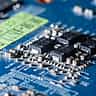 A detailed macro close-up of a blue electronic circuit board with microchips.