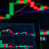 A close-up of a digital monitor displaying a financial candlestick chart with red downward trends.