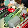 Fresh vegetables sit on a stainless steel grocery store checkout counter.