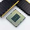 A computer processor and several black RAM sticks rest on a white surface.
