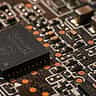 A detailed macro photograph of a microchip and intricate electronic components on a printed circuit board.