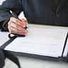 A close-up of a person signing a formal business document with a pen.