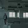 A single employee walks past rows of empty desks in a dimly lit office space.