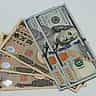A close-up view of United States one hundred dollar bills resting on top of Japanese ten thousand yen notes.