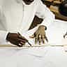 Close-up of a professional's hands using a pencil and ruler to draft architectural blueprints.