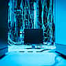 A dense, chaotic tangle of illuminated blue network cables surrounding a blank monitor in a dark server room.