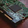 A macro close-up of a prominent black microchip mounted on a green computer circuit board.