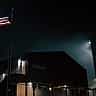 A large American flag is displayed on the side of the Stargate building at night.