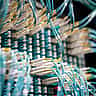 Close-up of bright teal fiber optic cables plugged into a high-density data center network switch.