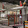 A large automated material handling machine operates on a production line inside a modern factory.