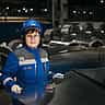 A woman in safety gear inspects large metal sheets in a modern industrial manufacturing setting.