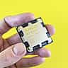 A hand holds an AMD Ryzen processor against a bright yellow background.