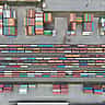 An aerial view of colorful shipping containers arranged in stacks of varying sizes at a storage terminal.