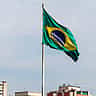 The Brazilian flag waves over the dense urban skyline of São Paulo.