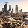 A sprawling view of the Riyadh skyline featuring modern skyscrapers rising above low-lying buildings.