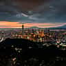 A sweeping view of the modern Taipei skyline at sunset, anchored by the towering Taipei 101 skyscraper.