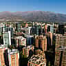 Aerial view of the modern financial district skyline in Santiago, Chile, with the Andes Mountains in the background.