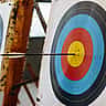 An arrow sits perfectly centered in the yellow bullseye of a colorful archery target.