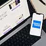 The American Express logo is displayed on a smartphone screen resting on a laptop keyboard.