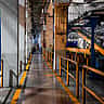A wide view of a modern industrial factory floor featuring heavy manufacturing machinery and painted yellow safety walkways.