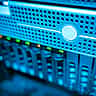 A close-up view of glowing blue lights on a modern network server rack in a dark data center.
