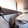 A white electric vehicle is plugged into a charging station in a modern indoor facility.