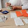 A person uses a calculator next to a small stack of cash on a wooden desk.