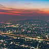 A sprawling aerial view of the Seoul city skyline illuminated at dusk under a dramatic, colorful sunset sky.
