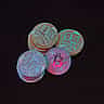 A stack of physical gold Bitcoin tokens sitting in heavy shadow against a pitch-black background.
