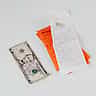 A five-dollar bill lies next to multiple printed shopping receipts on a light surface.