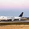 A white Saudia Cargo airplane taxis on an airport runway at twilight.