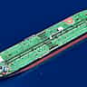 An aerial view of a massive green oil tanker sailing through deep blue ocean waters.