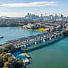 An aerial view of the Sydney skyline, harbor, and bridges on a bright sunny day.