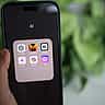 A hand holds a smartphone displaying a folder of artificial intelligence apps, including Anthropic's Claude.