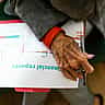 A close-up of an elderly person's hand holding a pen over a document titled 'financial reports' with a line chart.