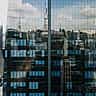 A modern glass skyscraper reflects the dense urban skyline of São Paulo.