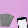 Two minimalist smart cards and a smartphone resting on a vibrant pink background.