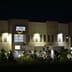 An illuminated Amazon warehouse building at night with glowing blue signage.