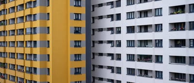 A modern apartment building facade split visually between bright yellow and clean white sections.