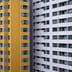 A modern apartment building facade split visually between bright yellow and clean white sections.