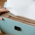 Hands placing a crisp white document into an organized blue accordion file on a wooden desk.