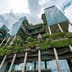 A striking modern skyscraper integrates lush vertical gardens and cascading plants into its eco-friendly architectural design.