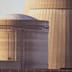 A close-up of concrete nuclear reactor buildings bathed in warm golden sunlight.