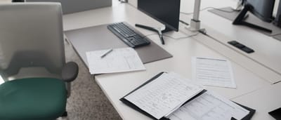 Official business forms and documents arranged neatly on a modern office desk next to a computer monitor.