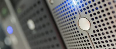 A close-up of a modern metal server faceplate with glowing blue LED indicators in a data center.