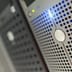 A close-up of a modern metal server faceplate with glowing blue LED indicators in a data center.